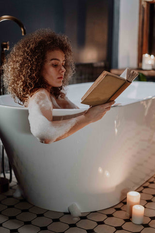 Mixed-race woman sitting in spa tub reading a book