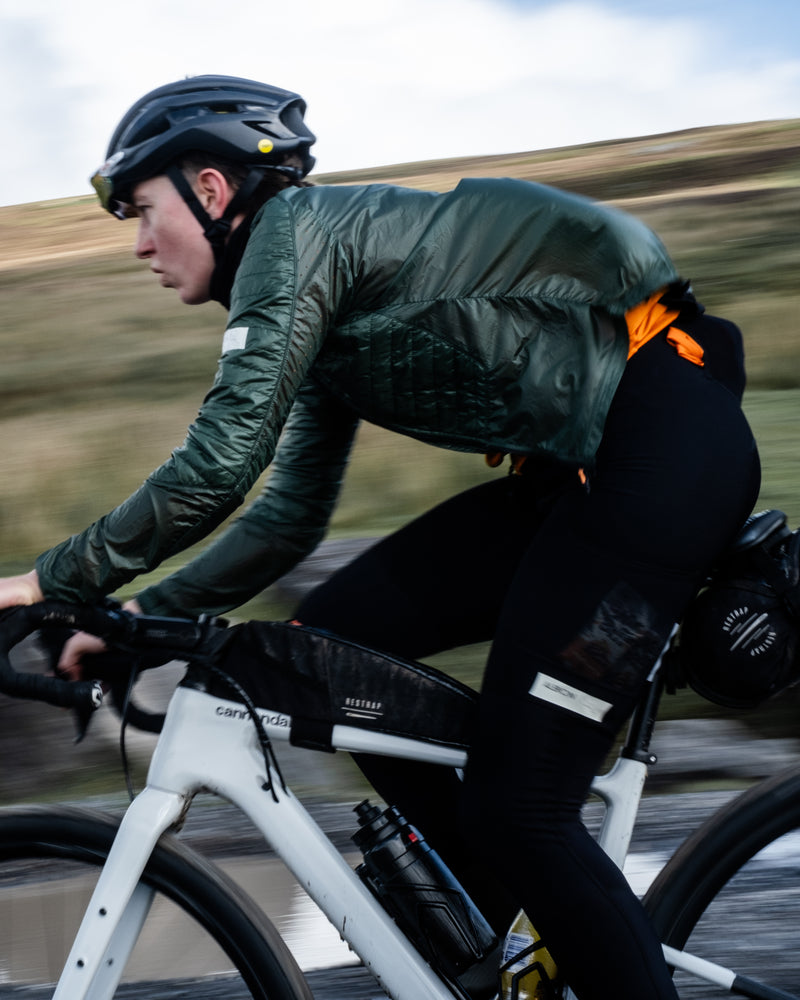 Woman riding a bike wearing a green insulated cycling jacket