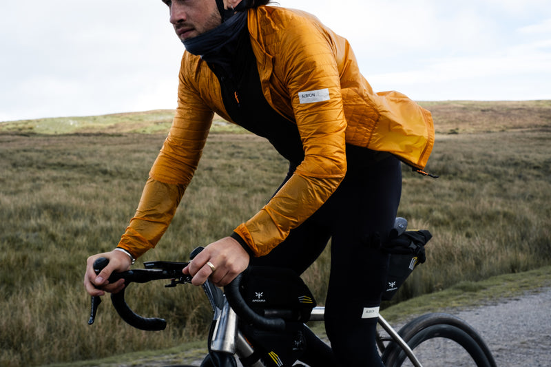 Man riding a bike in the countryside wearing a yellow insulated cycling jacket