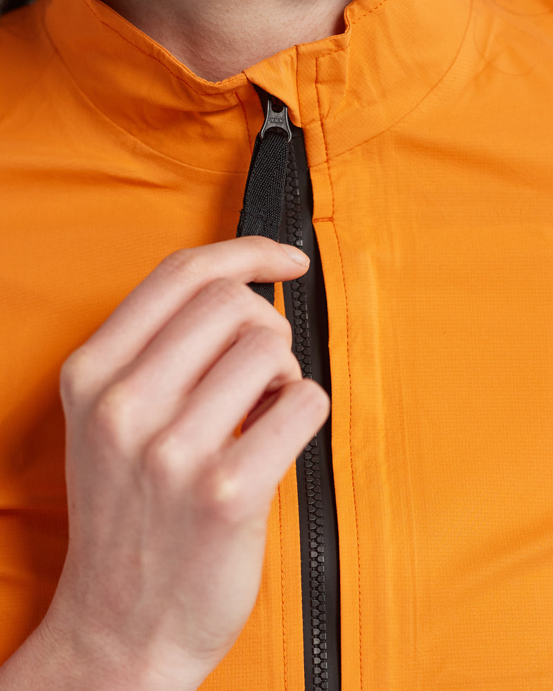 Close up of a woman holding the zip of an orange rain jacket