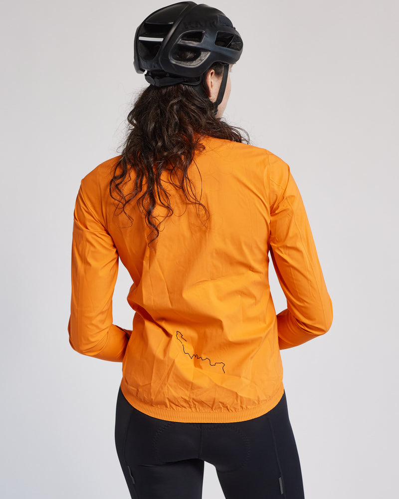 Woman wearing orange jacket and helmet seen from behind.