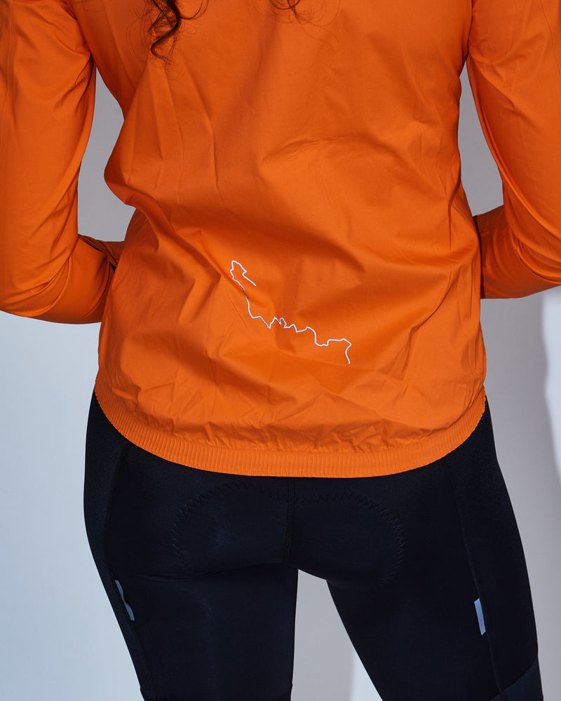 Woman wearing an orange rain jacket with reflective logo