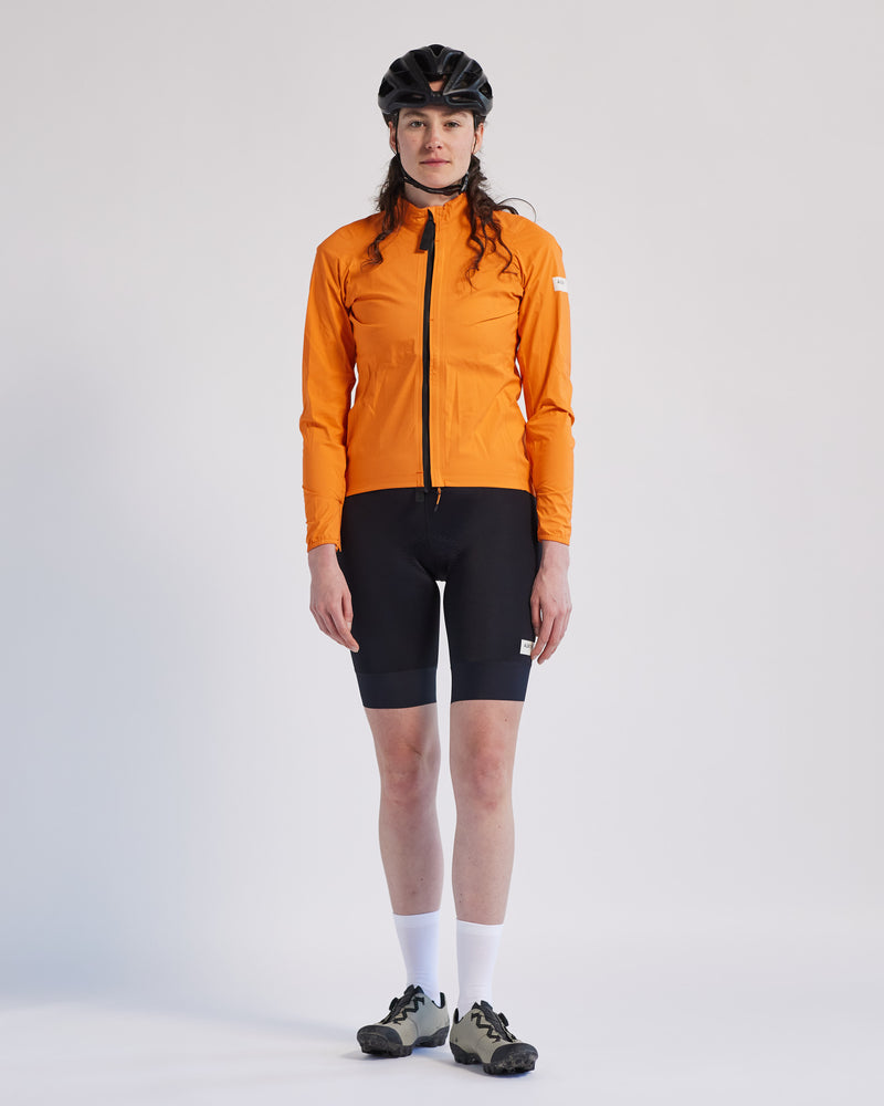 A woman in an orange jacket and black shorts