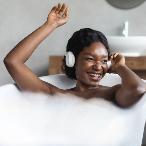 Woman happily bathing while enjoying music to relax.