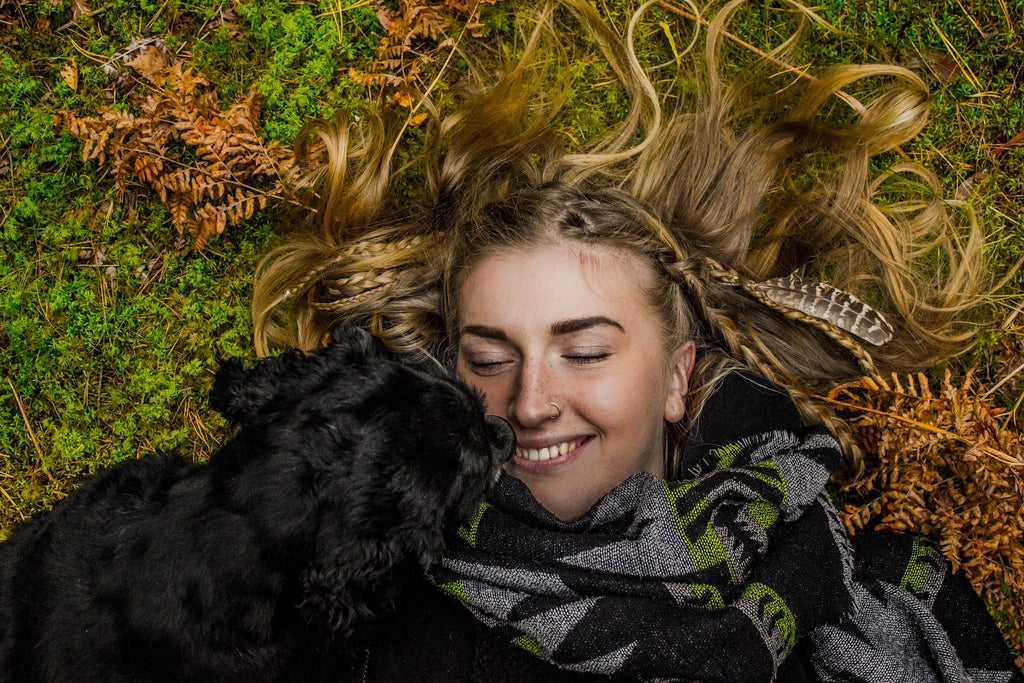 Frau kuscheld mit Hund auf der Wiese