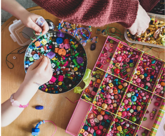 Hands crafting with colorful beads and buttons.