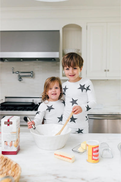 Siblings baking together in star-patterned pajamas.