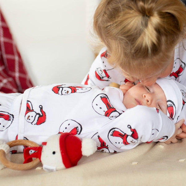 Newborn and his sibling wearing kids christmas pajamas.