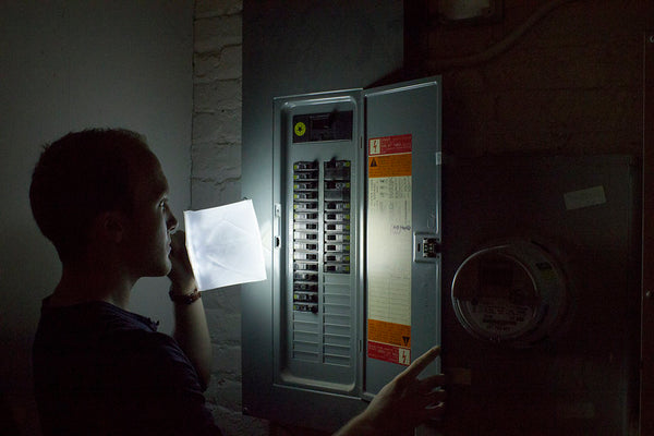 Man looks at electrical panel with LuminAID lantern