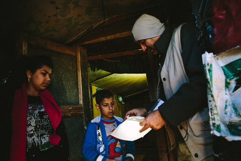 Convoy of Hope volunteer shows a Syrian refugee family how to use LuminAID solar lights