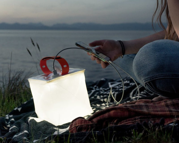 Individual on a blanket with their lantern near water