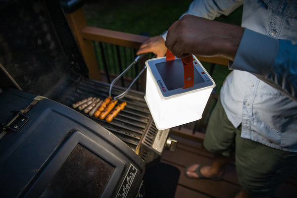 Source: Nick Zupancich. Person grills hot dogs and holds LuminAID lantern.