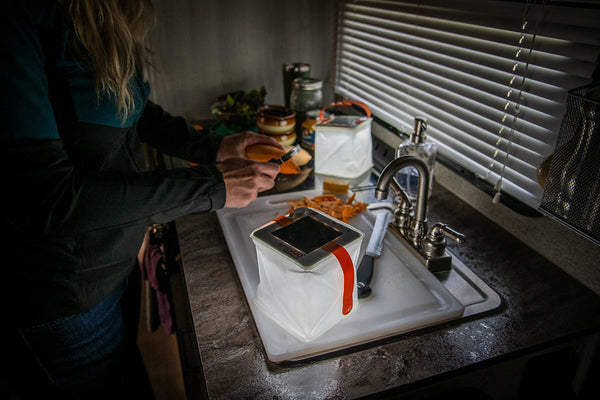 Woman peeling potatoes in a power outage with her LuminAID. Source: Megan McKay