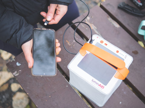 Person plugging phone into lantern charger