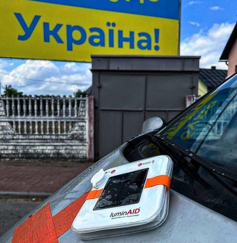 A LuminAID lantern charging on a car, in front of a sign that says Ukraine in Ukranian