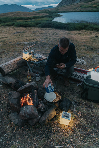 Person cooking with cast-iron skillet over a fire. Source: None Applicable