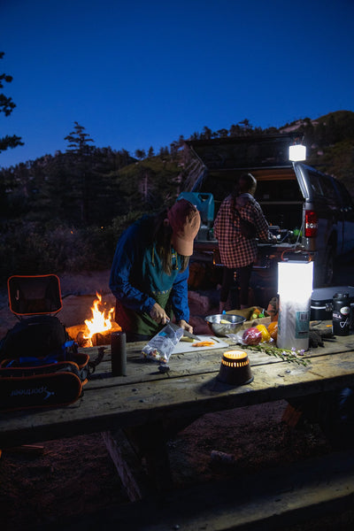 Person preparing dinner by a campfire. Source: Evan France