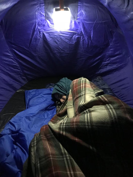 Person sleeping with a jacket and blanket in a tent. Source: Ruhi Akhtar, Love Without Borders