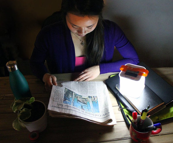 Woman reads newspaper with LuminAID Nova lantern