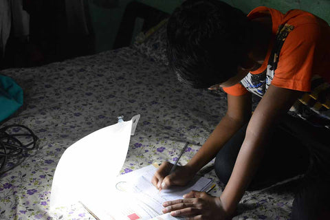 Child using light to do homework in dark.