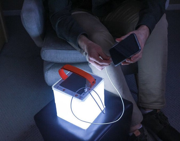 Person charges phone using lantern. Source: (Not listed)