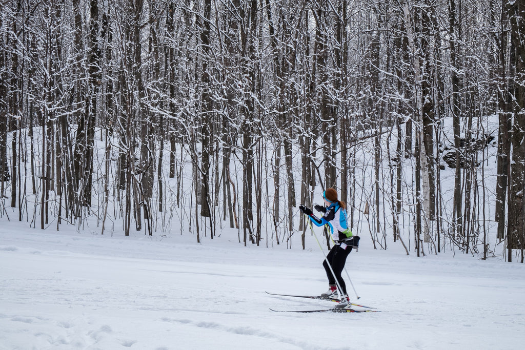 Woman cross-country skiing in a snowy forest.