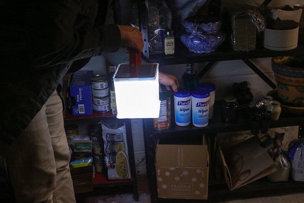 Person with lantern reaches for supplies on shelf