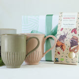 Green gift wrapping with chocolate and two mugs