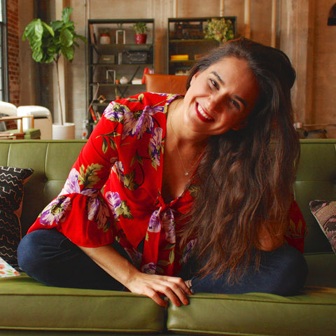 Kasey Dreier sitting cross-legged on couch smiling