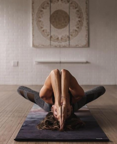 Girl doing seated backbend with arms folded together on yoga mat