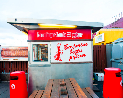 red hot dog stand with wooden table in front