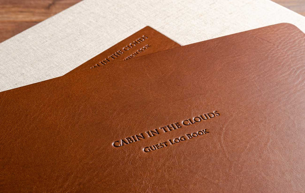 Blind embossing in leather guest book with a leather plaque in the back ground