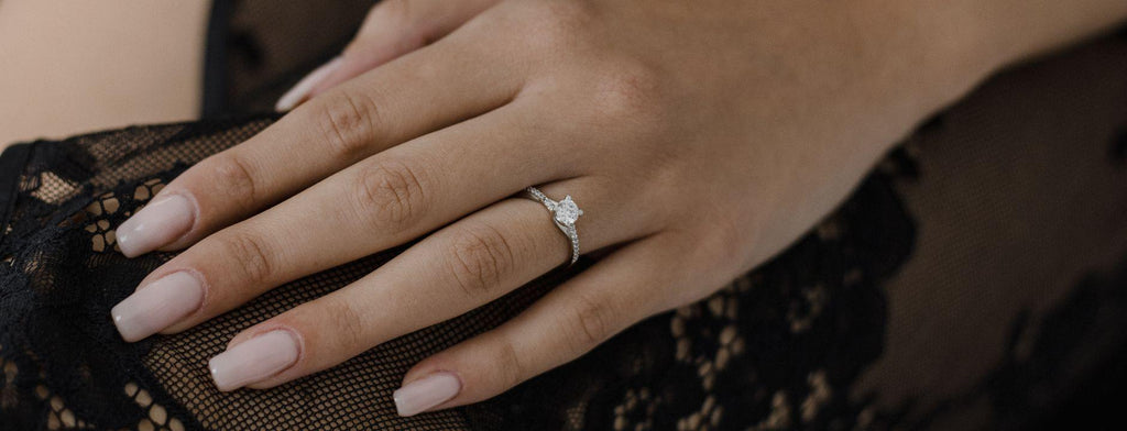 Λευκόχρυσο μονόπετρο με διαμάντι φορεμένο σε γυναικείο χέρι.