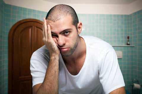 photo of a man holding his face.