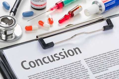 image of a clipboard with the word concussion on it with pills and syringes in the background.