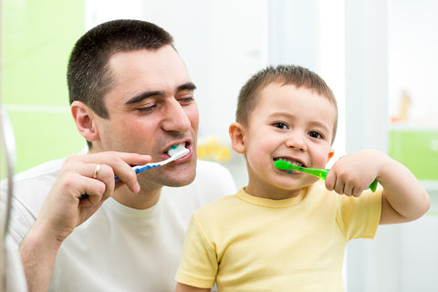 photo of father and son brushing their teeth together.