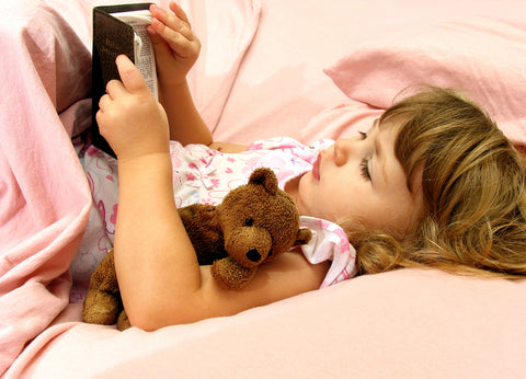 photo of a young girl reading her bible before sleep.