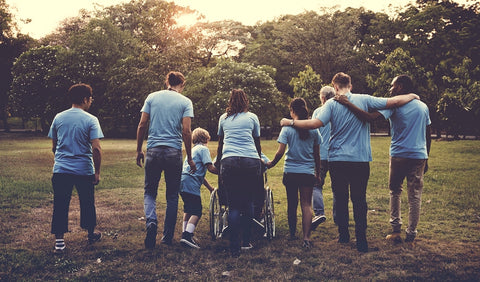 photo of a diverse multigenerational and differently abled group of people walking away in a field.