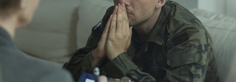 photo of a soldier with his hands together in prayer talking to a suited man.
