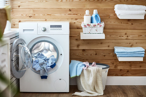 photo of a front load dryer and laundry spilling out in a laundry room.