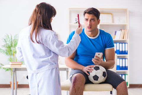 photograph of a doctor checking a soccer player for concussion.