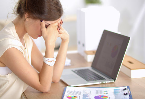 photo of woman sitting at her laptop with her head in her hands.