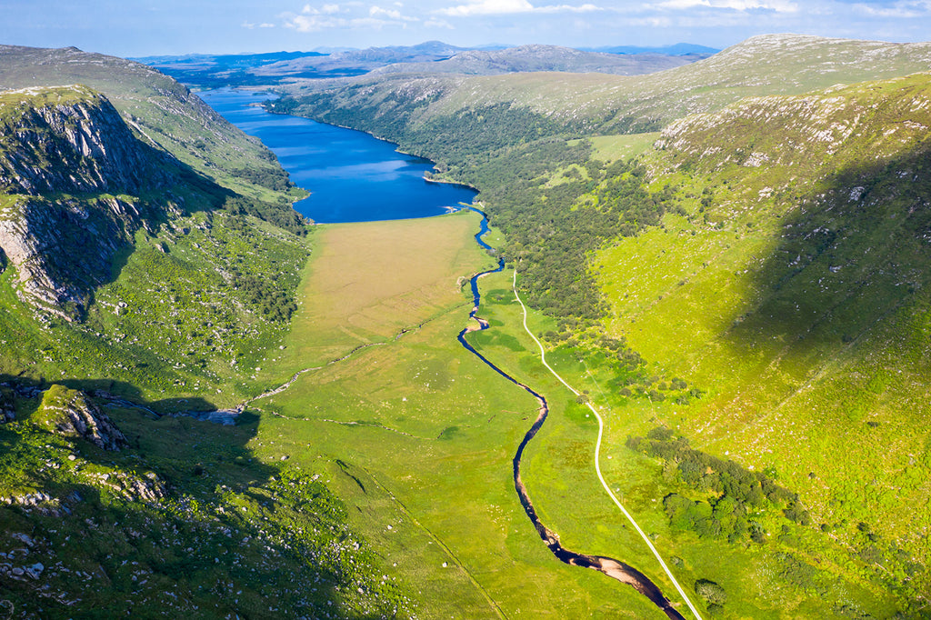 A sunny, aerial view of a valley, a river, a loch and the Derryveagh mountains in Glenveagh National Park, County Donegal, Ireland. 