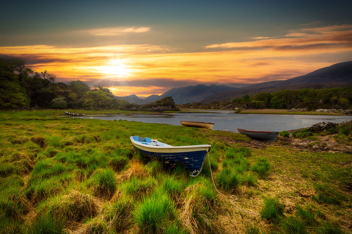 Landscape scene of boats by Killarney lake at sunset in County Kerry, Ireland.