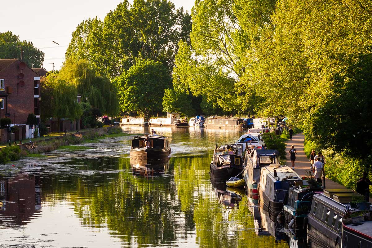 The beautiful and serene river lee by Hackney marshes with canal boats, green trees and wildlife.