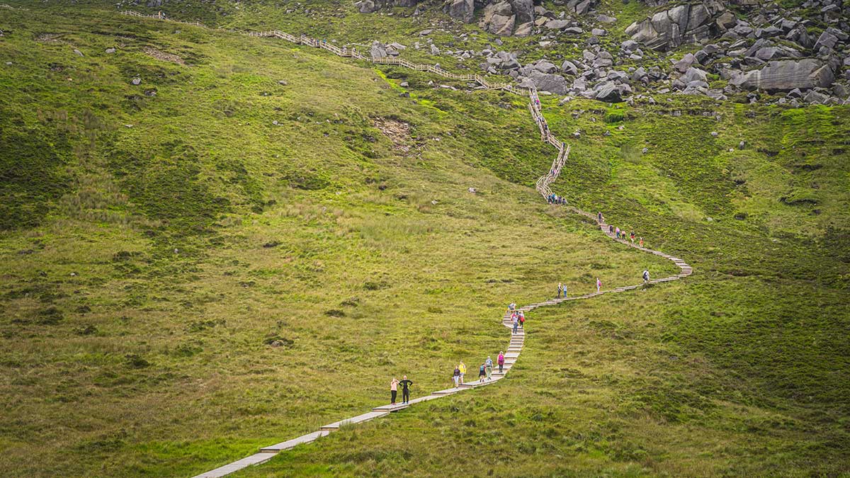People hiking the wooden boardwalk of the Cuilcagh Mountain Boardwalk Trail, Fermanagh, Northern Ireland.