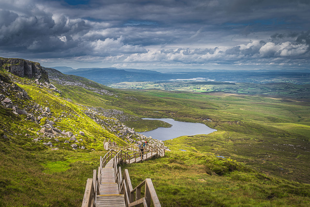 People hiking the steep boardwalk stairs of Cuilcagh Mountain with lake views in the Cuilcagh Mountain Park, County Fermanagh, Northern Ireland.