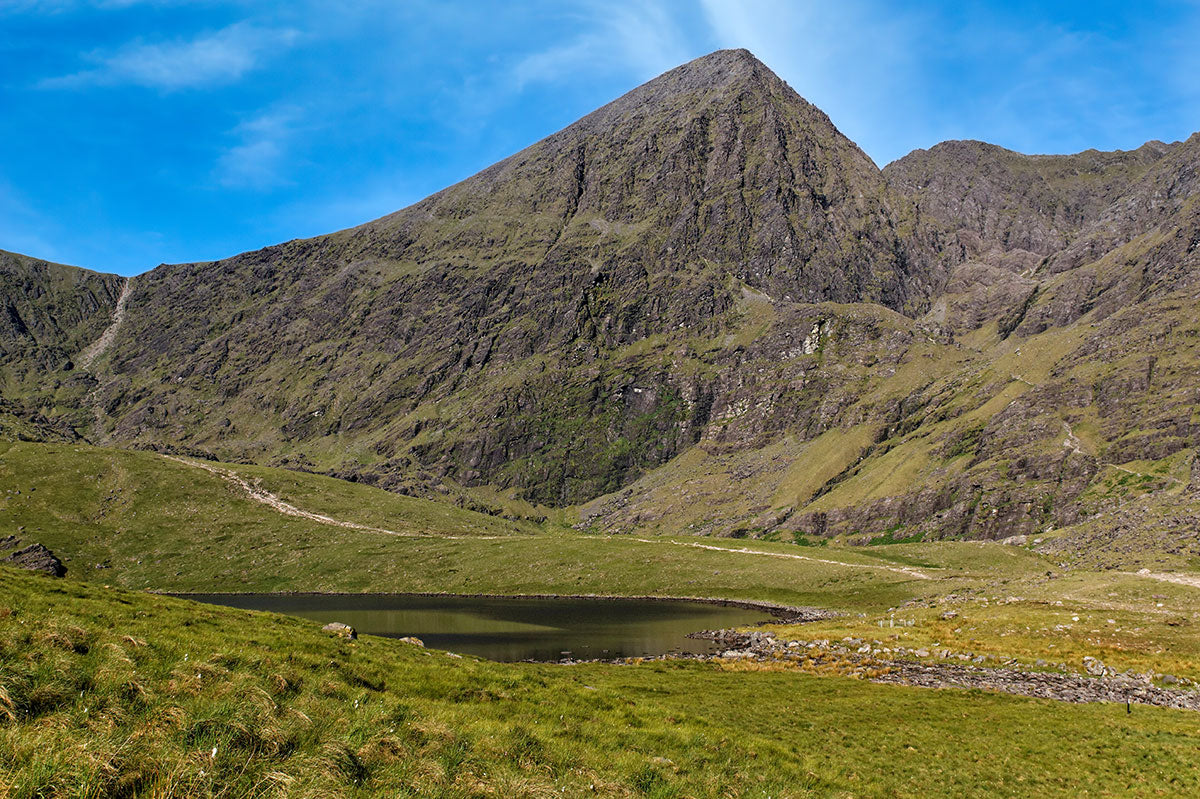 A landscape view of Lough Callee, green grasslands and Carrauntoohil, Ireland’s tallest peak, County Kerry.