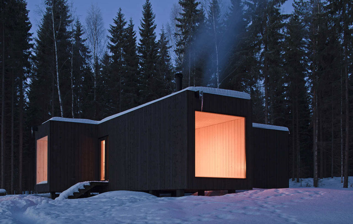 This minimalist lakeside cabin in Finland has a cross-shaped construction that offers distinctive views from each corner, designed to make the most of the sun at different times of the day, from morning to night.