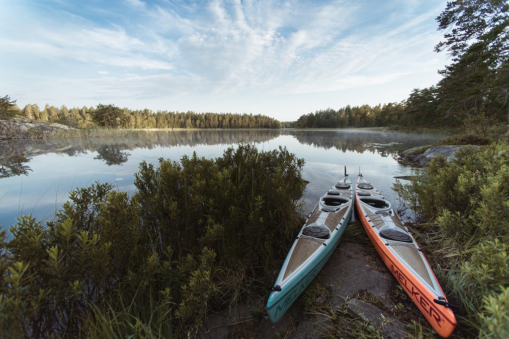 Kayaks pulled up on the bank with tranquil lake panorama in the background